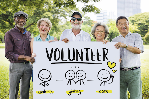 five people standing holding volunteer poster